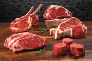 Certified Angus Beef® brand Prime Raw Middle Meat Cuts - Prime Raw-Middlemeat Variety, Standing Bone-in Ribeyes, Boneless ribeye, Porterhouses, Strip Steaks and Tenderloin Filets with herb sprigs on classic wood